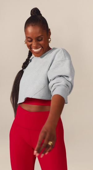 Issa Rae wearing a grey sweatshirt and red high-waisted midi leggings.
