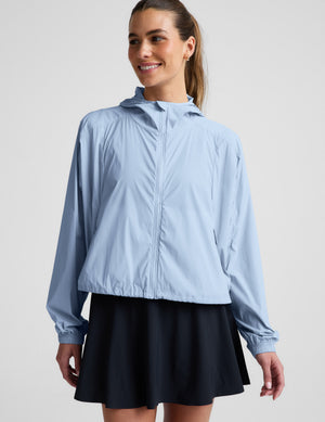 Woman wearing a light blue jacket and navy blue skirt against a plain background.