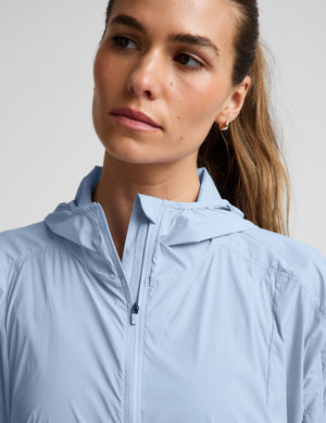 Woman wearing a light blue jacket and navy blue skirt against a plain background.