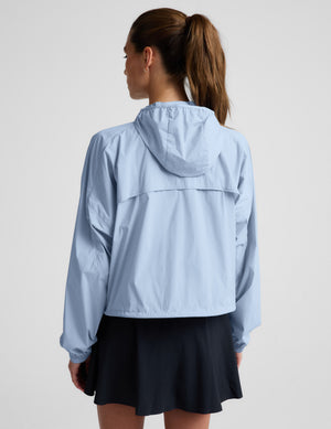Woman wearing a light blue jacket and navy blue skirt against a plain background.