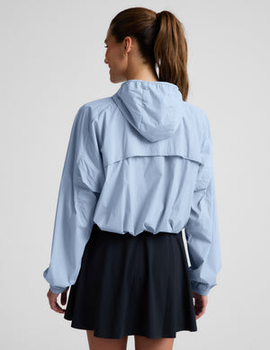 Woman wearing a light blue jacket and navy blue skirt against a plain background.