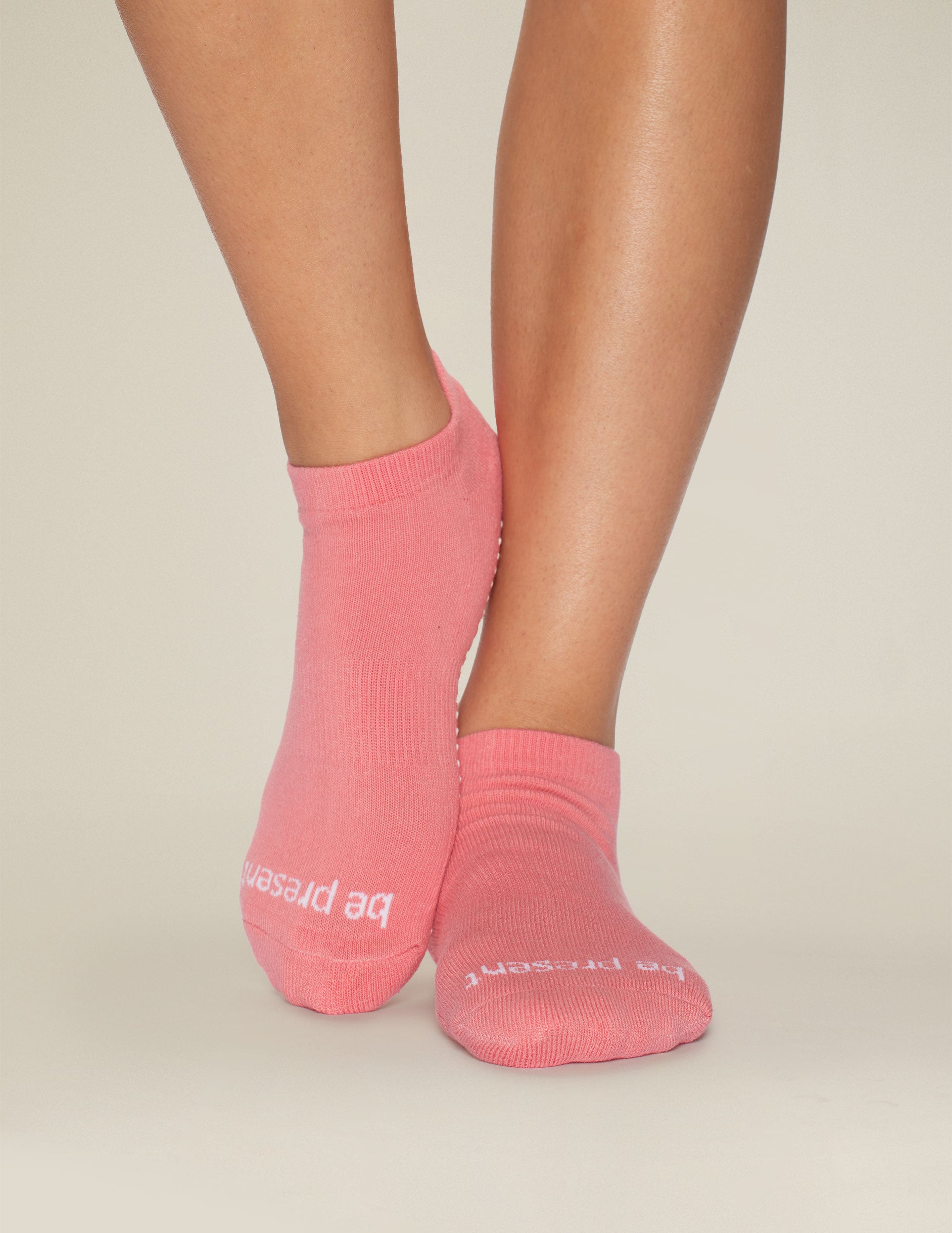 pink ankle grip socks with the mantra "be present" printed. 