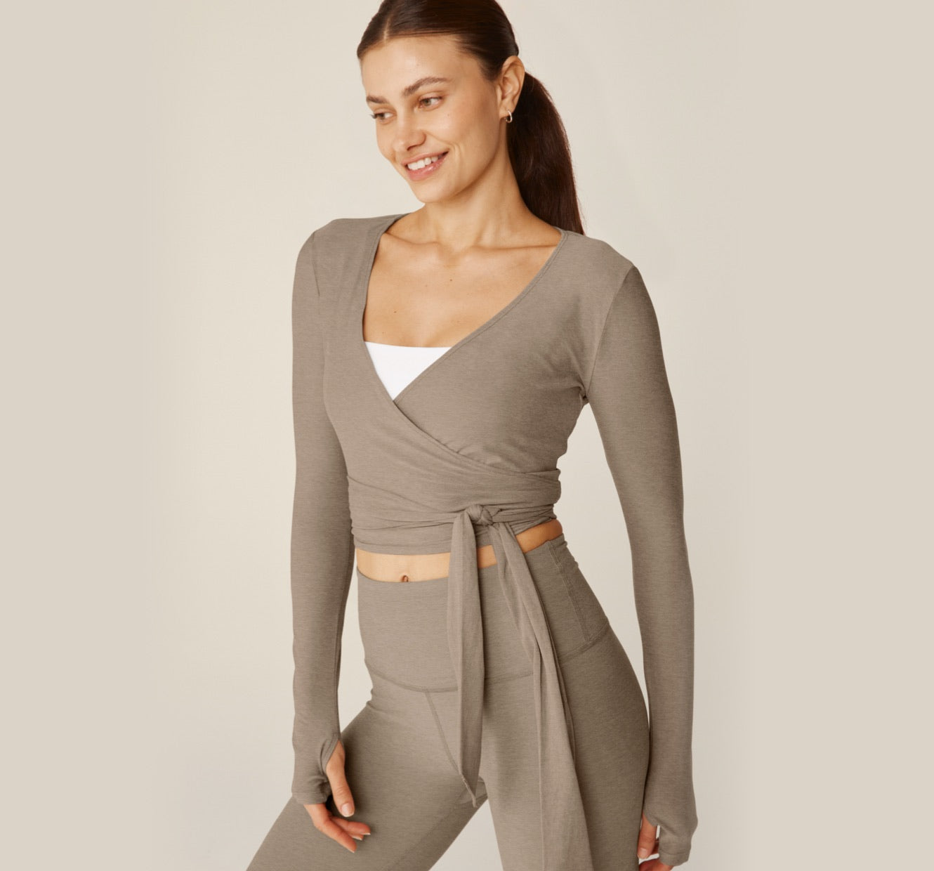 model is wearing a brown long sleeve wrap around top and brown high-waisted midi legging. 