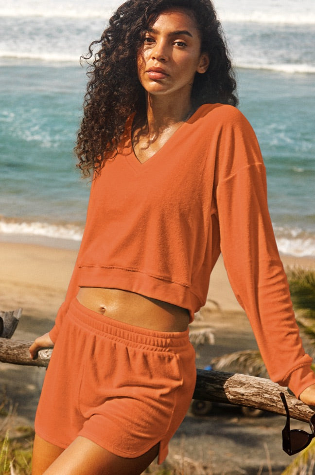 model is wearing an orange terry fabric pullover and orange terry shorts. 