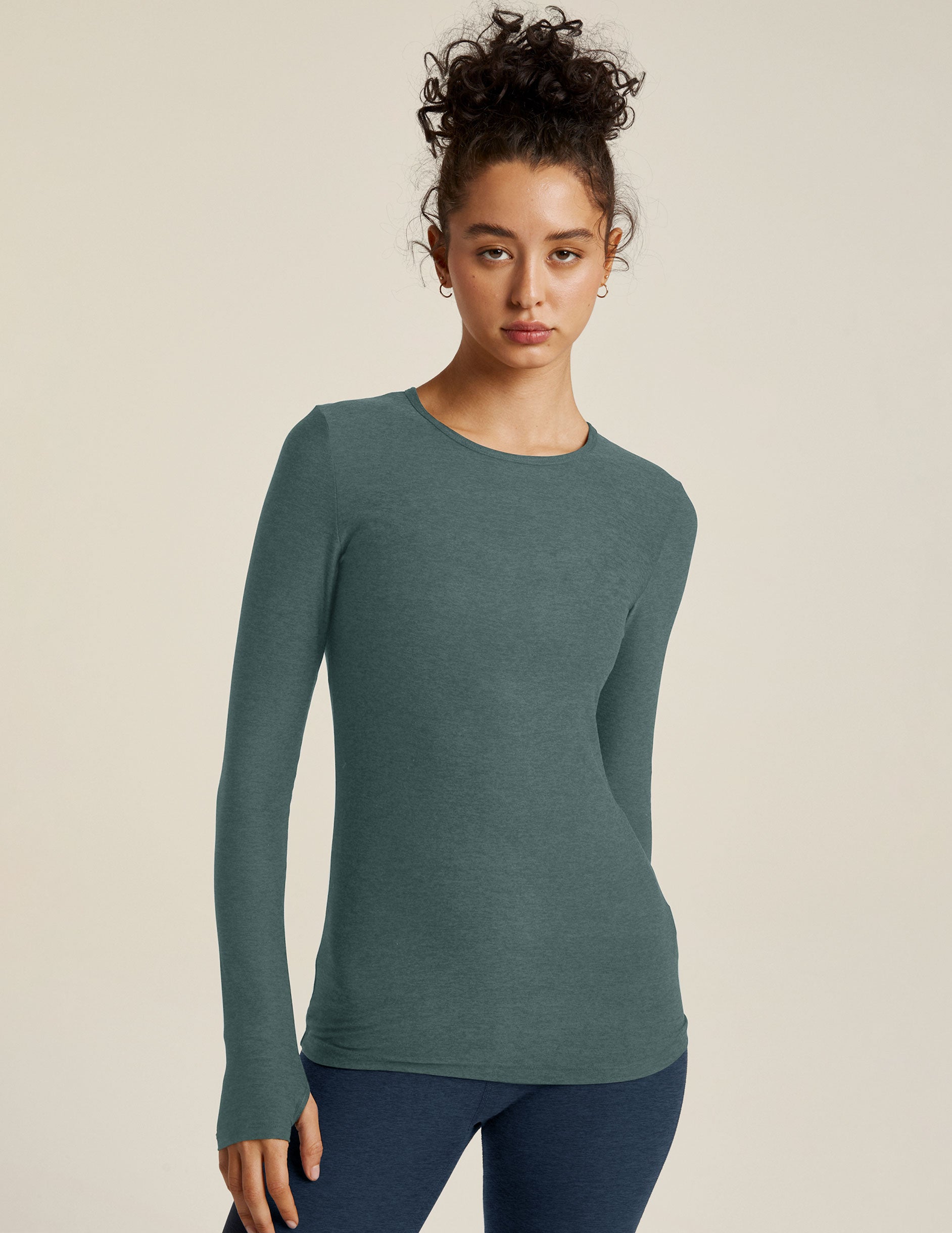 model is wearing a blue long sleeve crew neck top with thumb holes. 