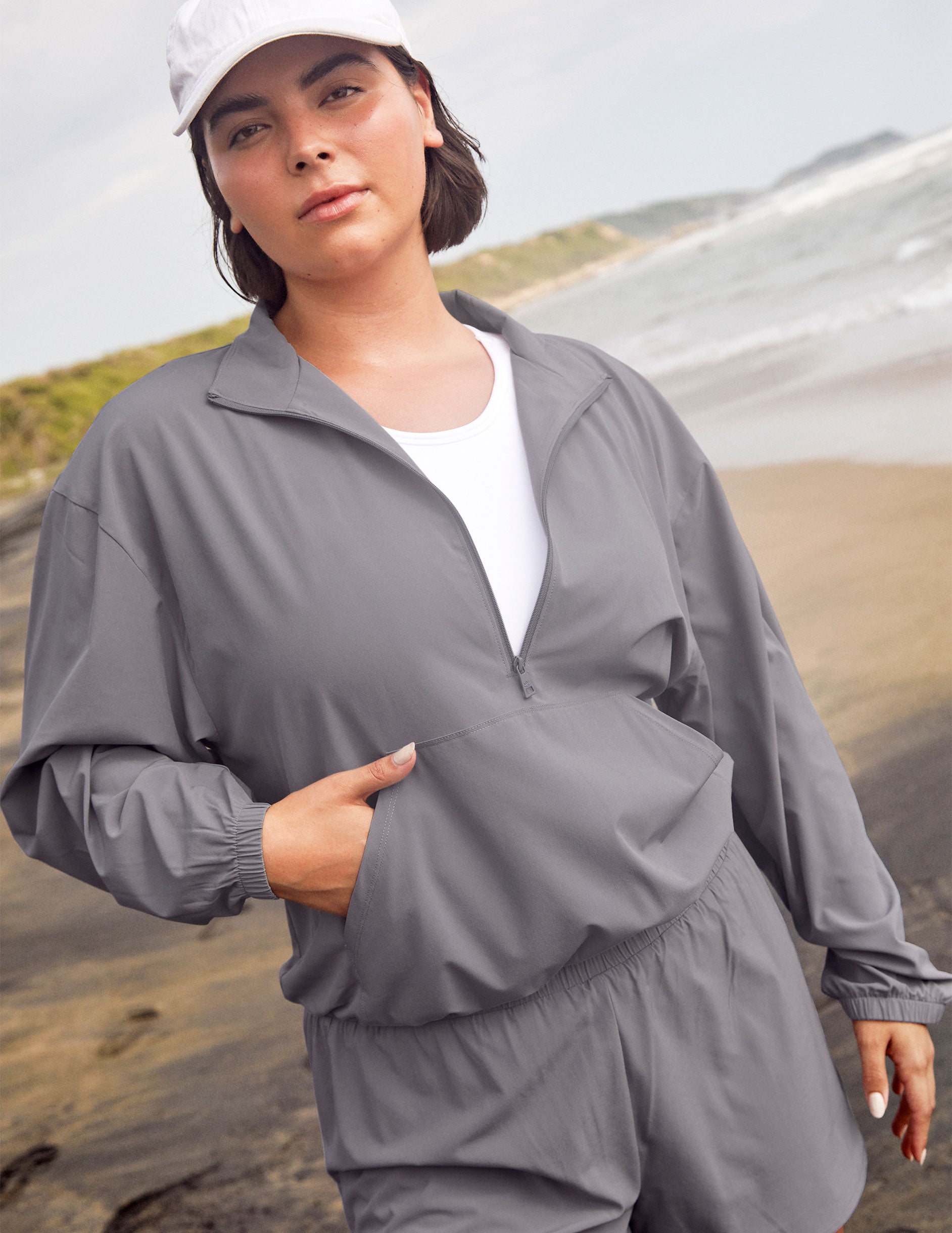 model is wearing a gray quarter zip jacket with a kangaroo pocket. 