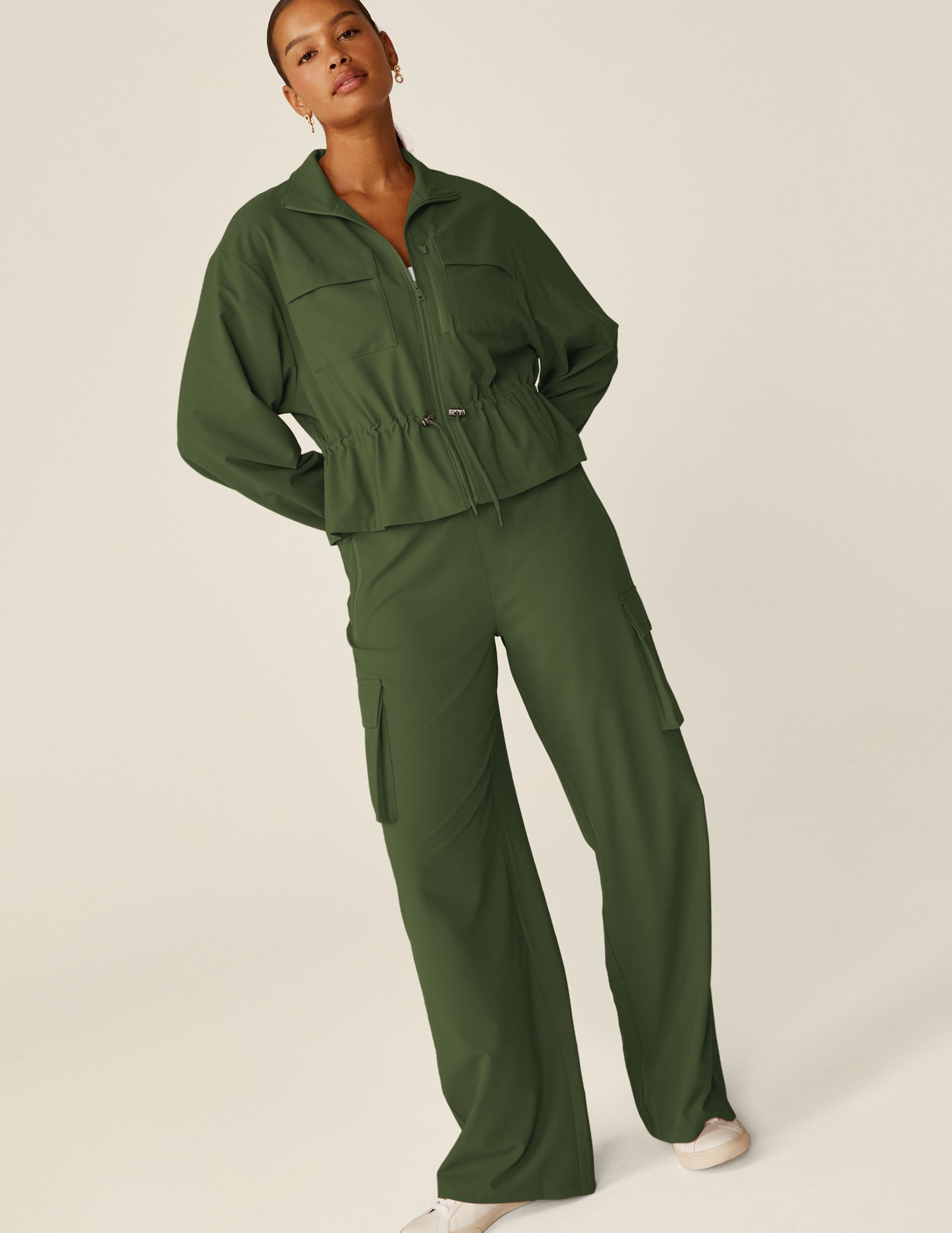 green zip-up jacket with a drawstring at waistband and cargo style pockets.