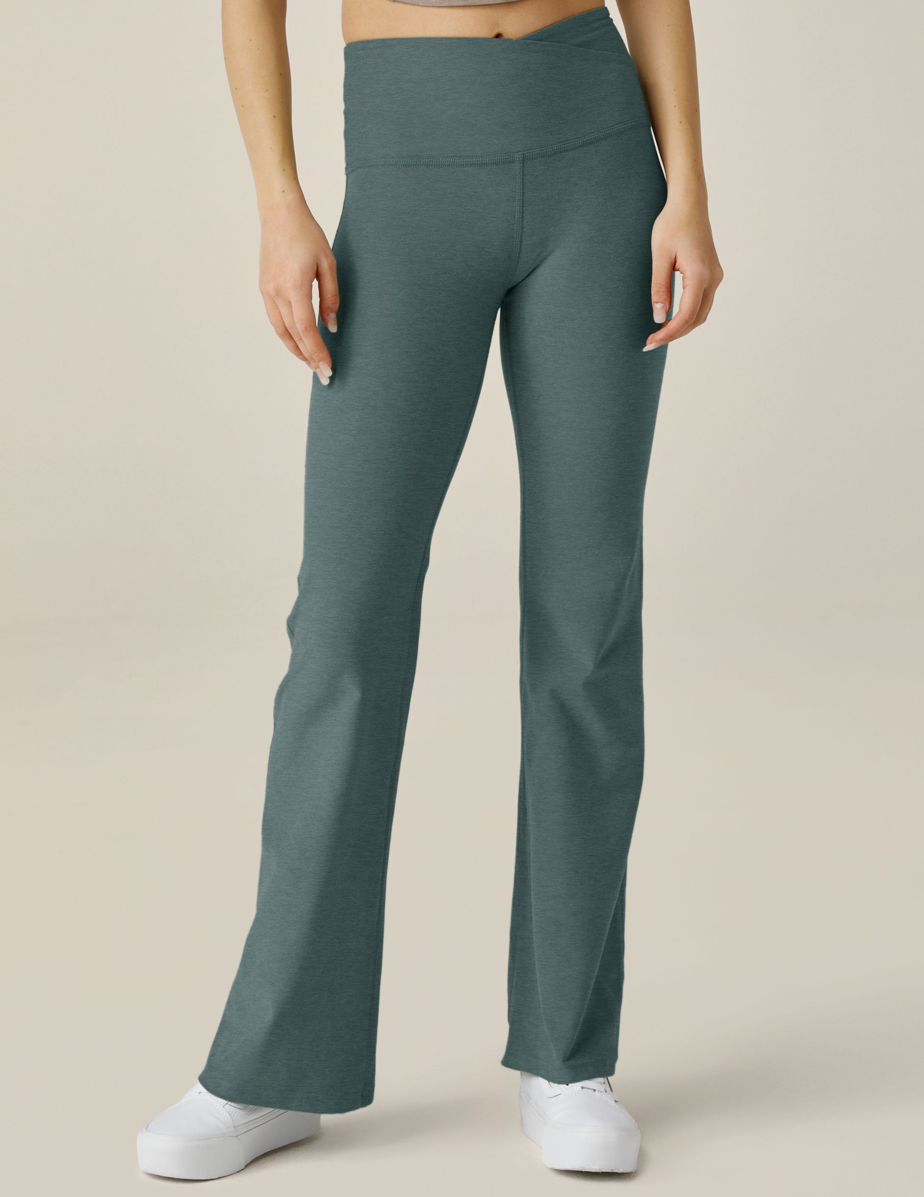 green high-waisted flare pants with a crossover detail on the front waistband. 