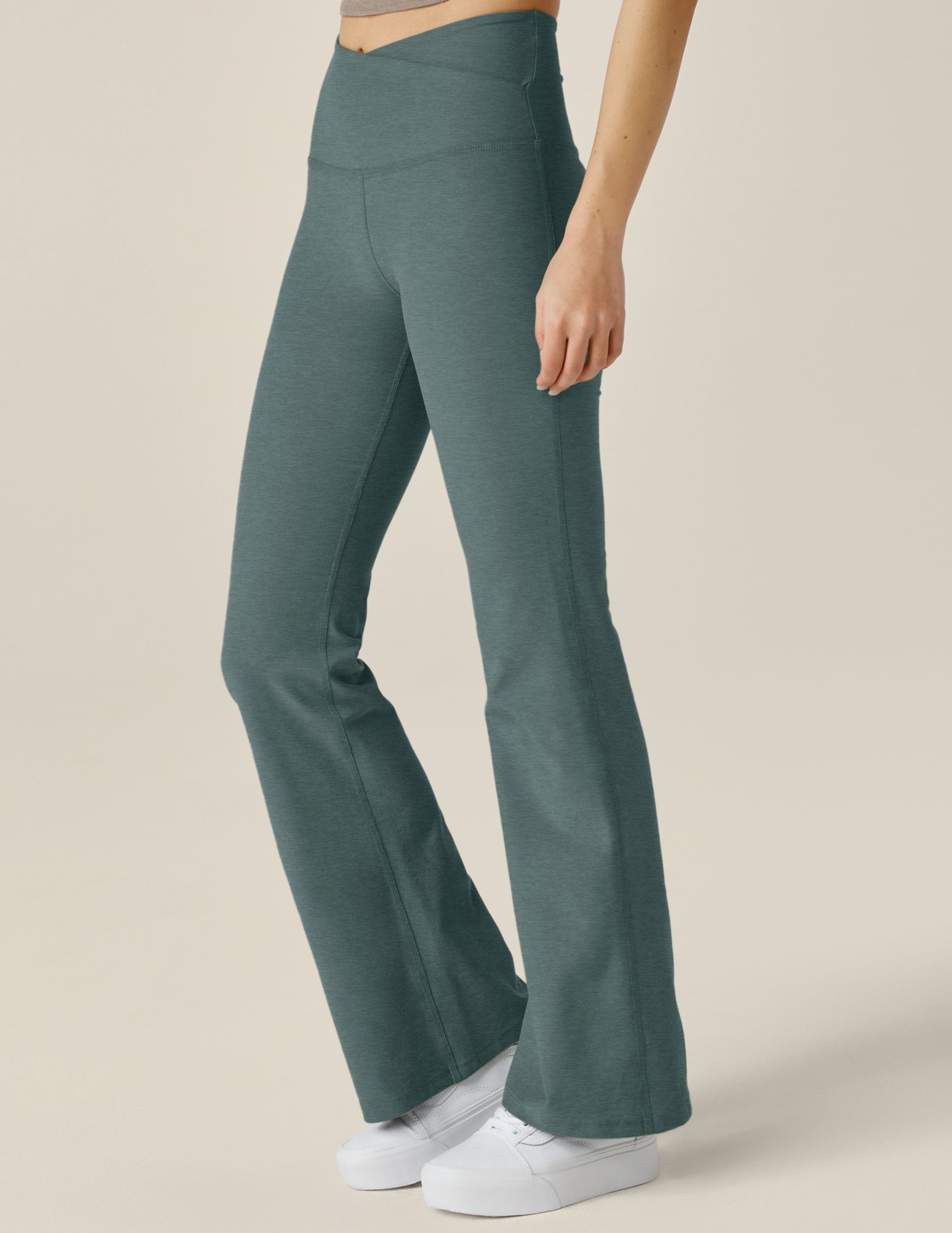 green high-waisted flare pants with a crossover detail on the front waistband. 