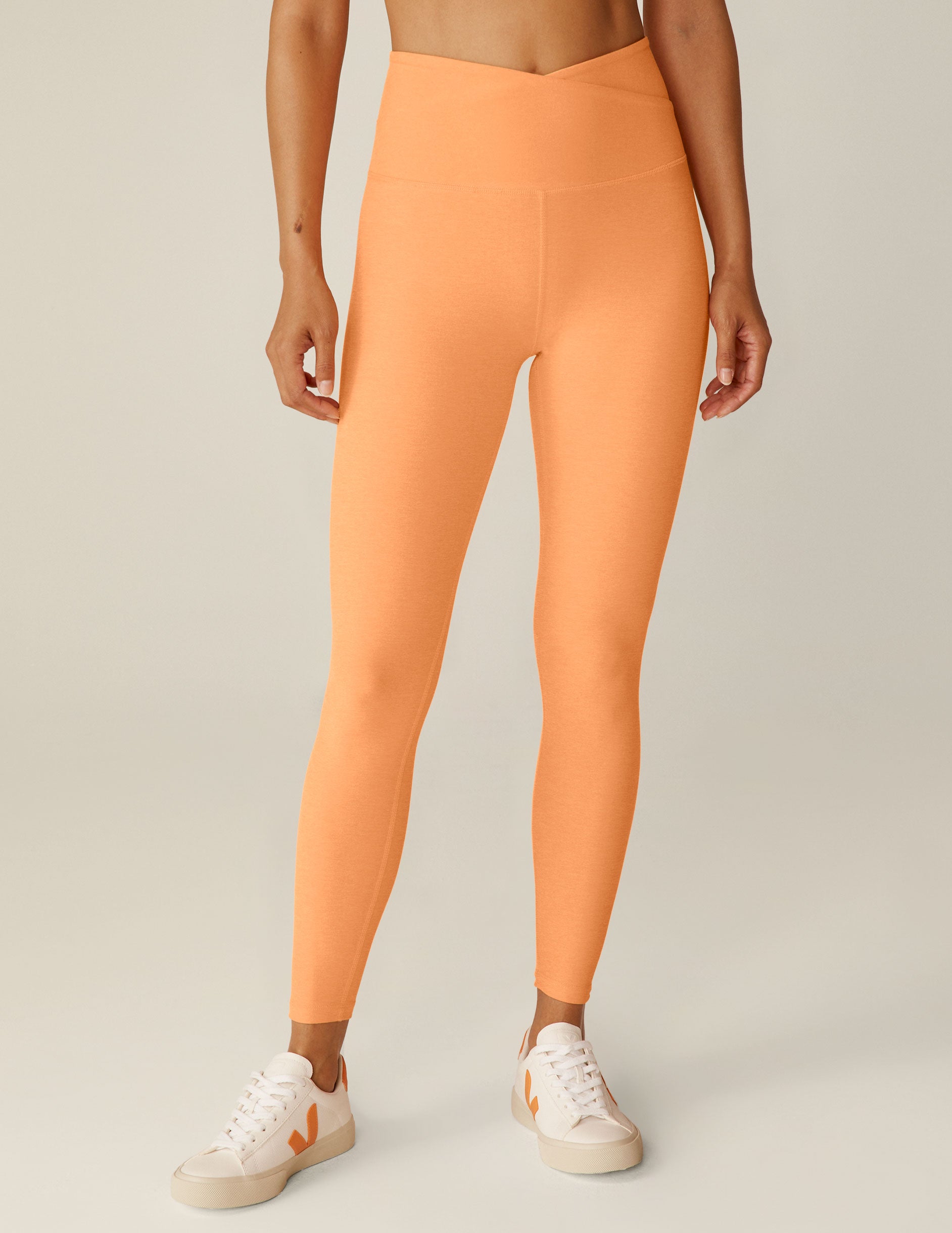 orange high-waisted midi leggings with a crossover detail on the front waistband. 