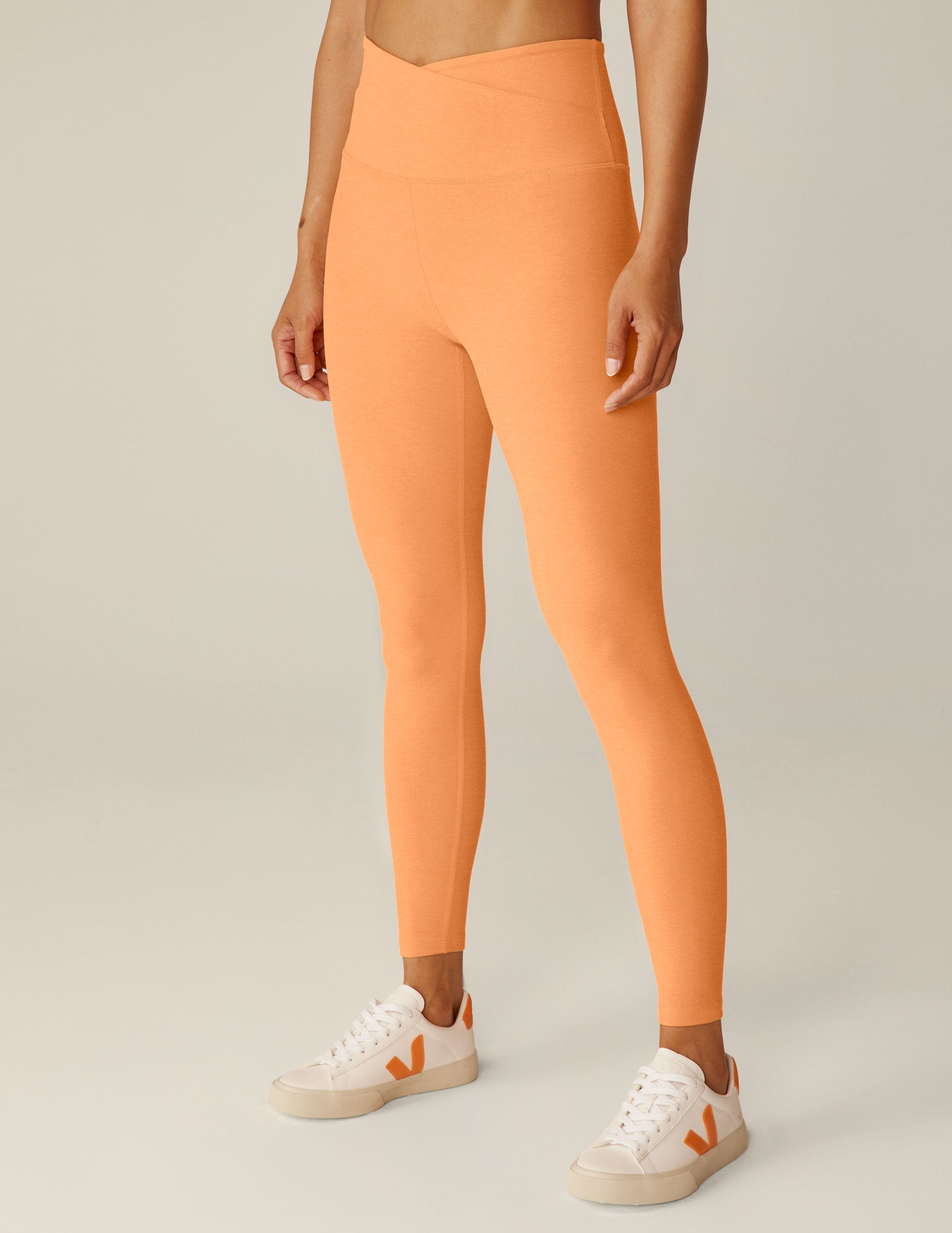orange high-waisted midi leggings with a crossover detail on the front waistband. 