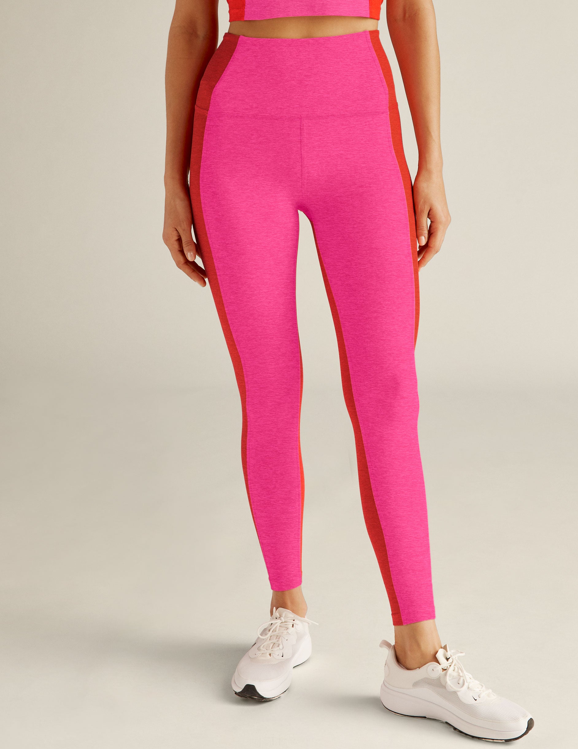 pink high-waisted midi leggings with red colorblock detailing on the sides. 