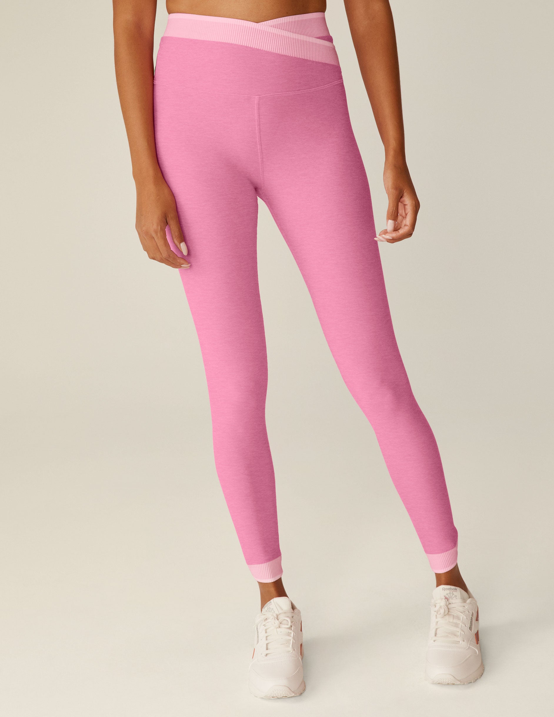 pink high-waisted midi leggings with a crossover and outline detailing on the waistband. 
