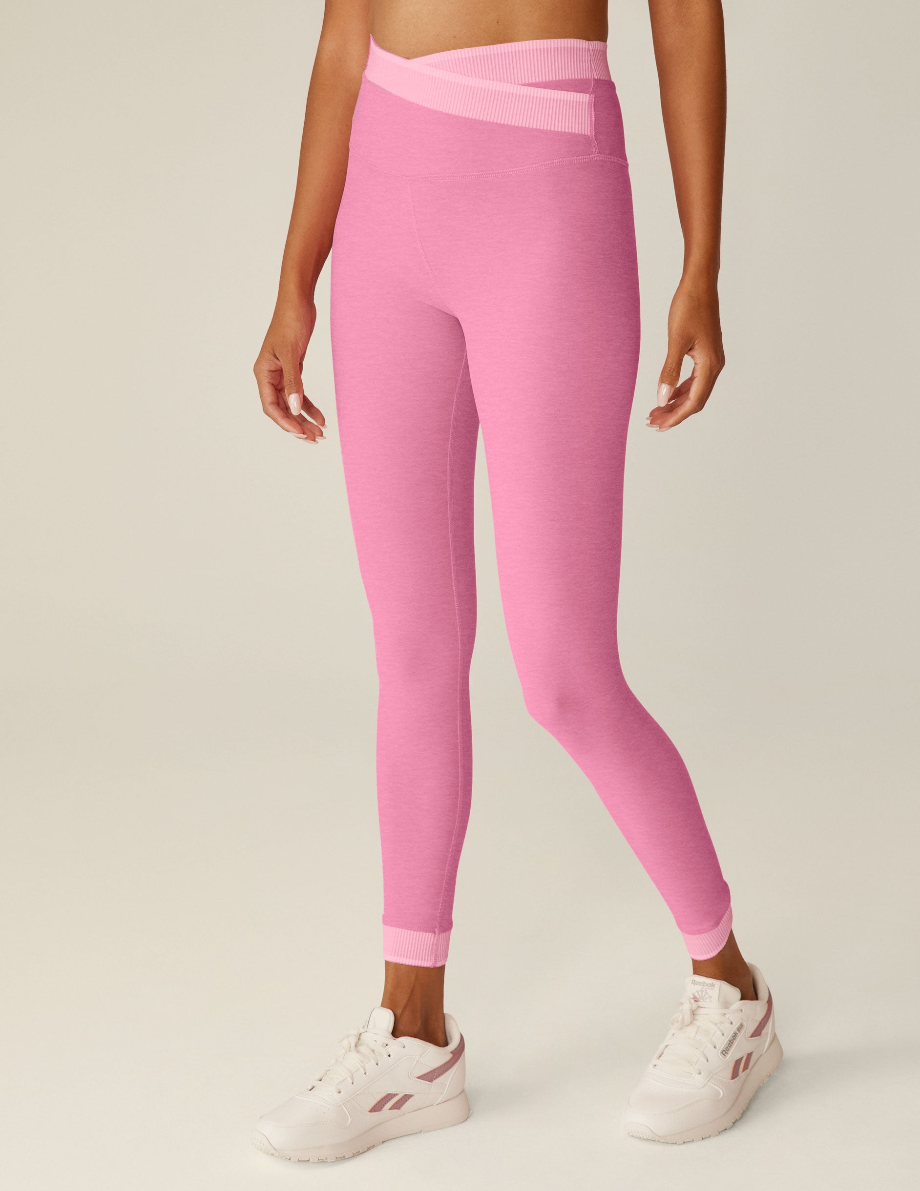 pink high-waisted midi leggings with a crossover and outline detailing on the waistband. 