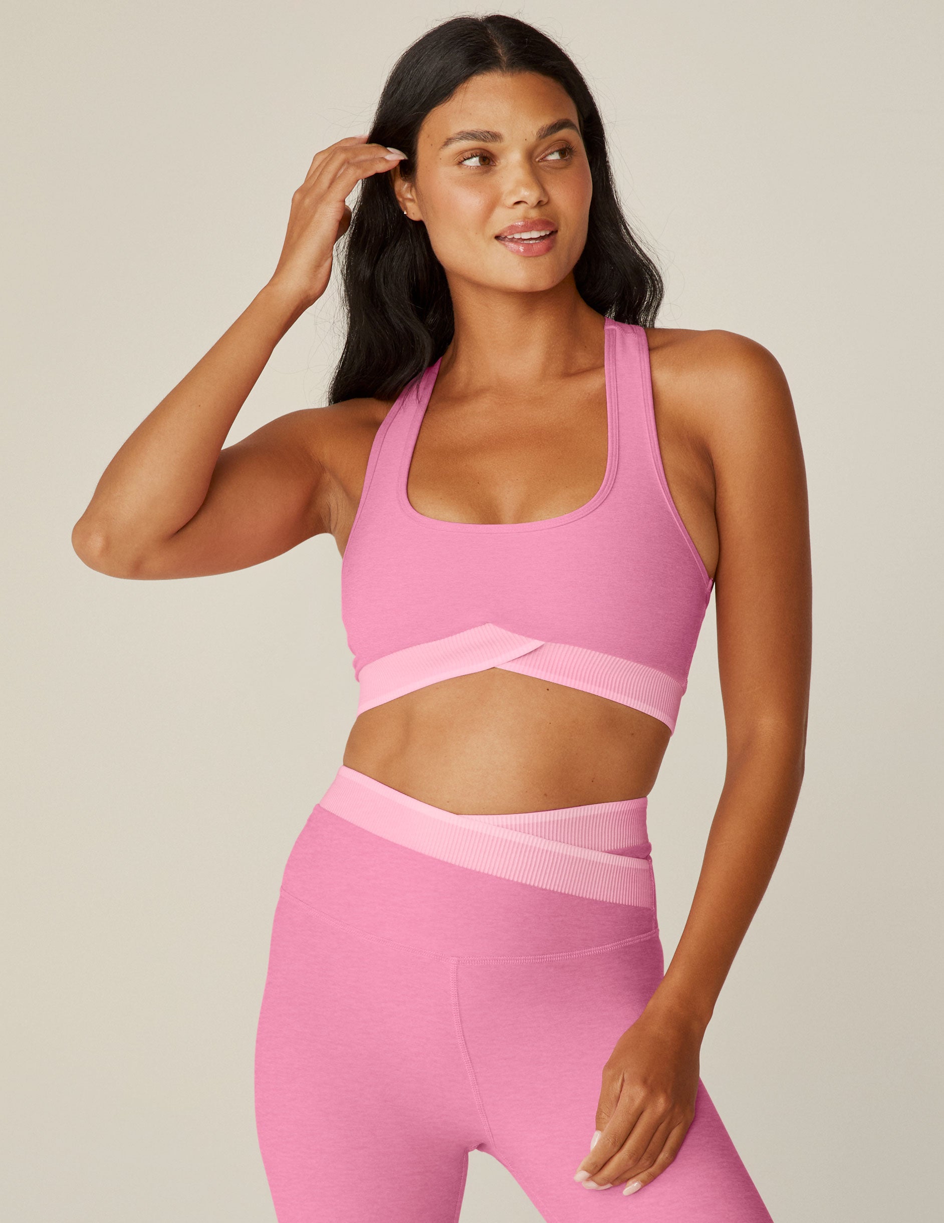 pink scooped neck racerback bra top with a front crossover and outlining detail. 