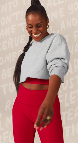issa rae wearing gray sweatshirt and red high-waisted leggings against a light background with text.