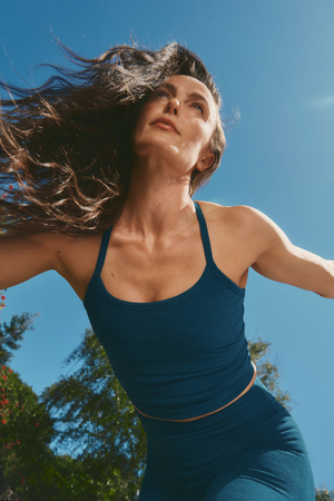 megan roup wearing a blue racerback cropped tank and blue biker shorts against a blue sky.