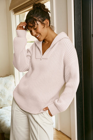 woman wearing a soft pink relaxed fit quarter zip knit sweater and white fleece pants. 