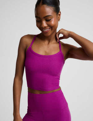 Woman wearing a purple racerback cropped tank and biker shorts against a plain background. 