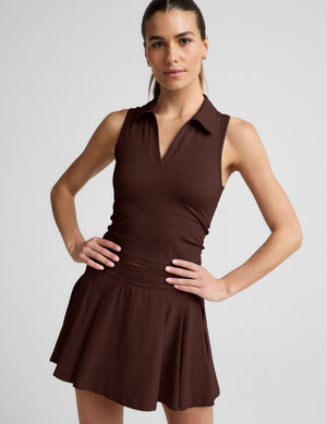 Woman wearing a brown sleeveless tank and skirt against a plain background. 