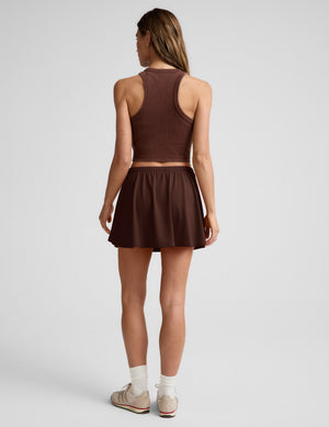 Woman wearing a brown sleeveless top and skirt on a white background. 