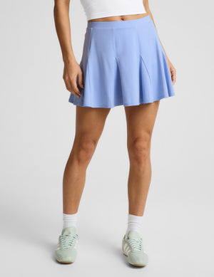 Woman wearing a white sleeveless top and a blue mini athletic dress against a plain background. 