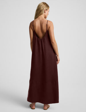 Woman wearing a brown maxi cupro dress against a plain background. 