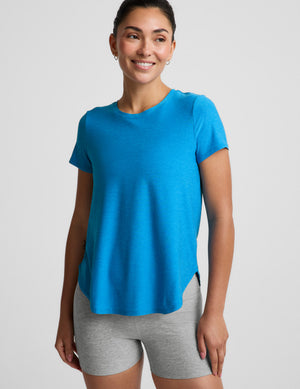 Woman wearing a blue t-shirt and gray biker shorts against a plain background. 