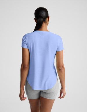 Woman wearing a light blue t-shirt and gray biker shorts against a plain background. 