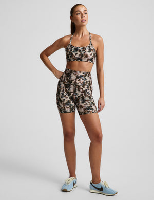 Woman in a printed sports bra and biker shorts against a plain background. 