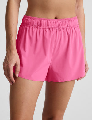 Woman wearing a pink sports bra and pink running shorts against a plain background. 