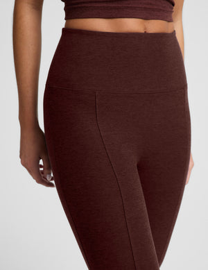 Woman wearing a brown cropped tank top and brown kick flare pants cropped pants against a plain background. 