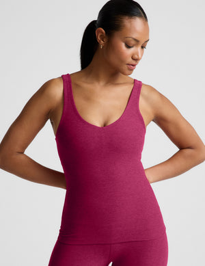 Woman wearing a red full length tank top and leggings against a plain background. 