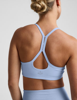 Woman wearing a light blue sports bra and biker shorts against a plain background. 
