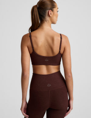 Woman wearing a brown sports bra and brown leggings against a plain background. 