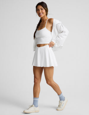 Woman wearing White You're A Force Skirt™ with a V-shaped waistline, paired with a white tank top and cream sneakers.