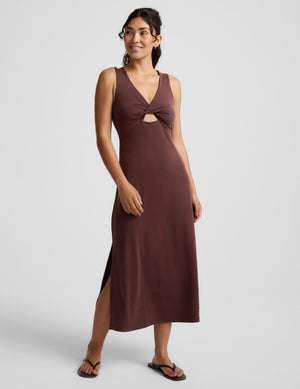 Woman wearing a brown sleeveless dress with a front center cutover on a light gray background. 