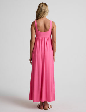 Woman wearing a pink maxi dress on a plain background. 