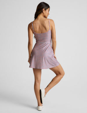 Woman wearing a gingham dress against a light gray background. 