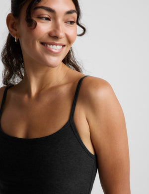 Woman wearing a black mini tank dress against a light gray background. 
