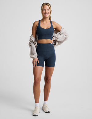 Woman wearing a navy blue cropped tank and biker shorts against a plain background. 