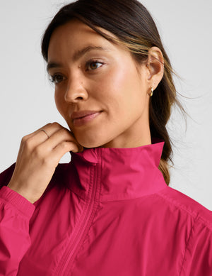 Woman wearing a red half-zip jacket and gray biker shorts against a plain background. 