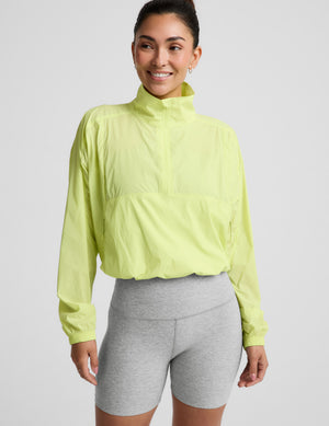Woman wearing a bright yellow jacket and gray shorts on a light gray background. 