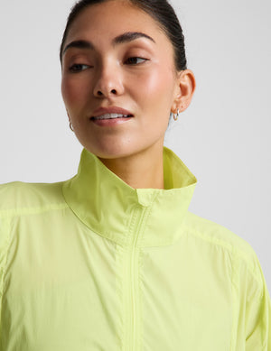 Woman wearing a bright yellow jacket and gray shorts on a light gray background. 