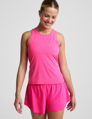 Woman wearing a pink tank top and pink running shorts against a plain background. 