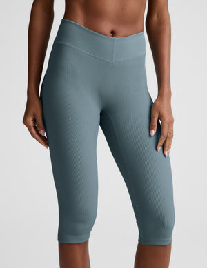 Woman wearing a blue ribbed bra and blue ribbed pedal pushers against a plain background. 