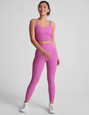 pink ribbed cropped tank top with a soft V neckline front and back​, an overlapping front neckline detail​, and a lining shelf bra​. 
