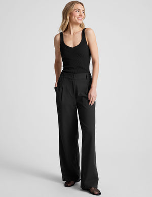 black ribbed tank top with a soft V neckline front and back​, overlapping front neckline detail, and a performance lining shelf bra. Tank hits at a high hip length. 