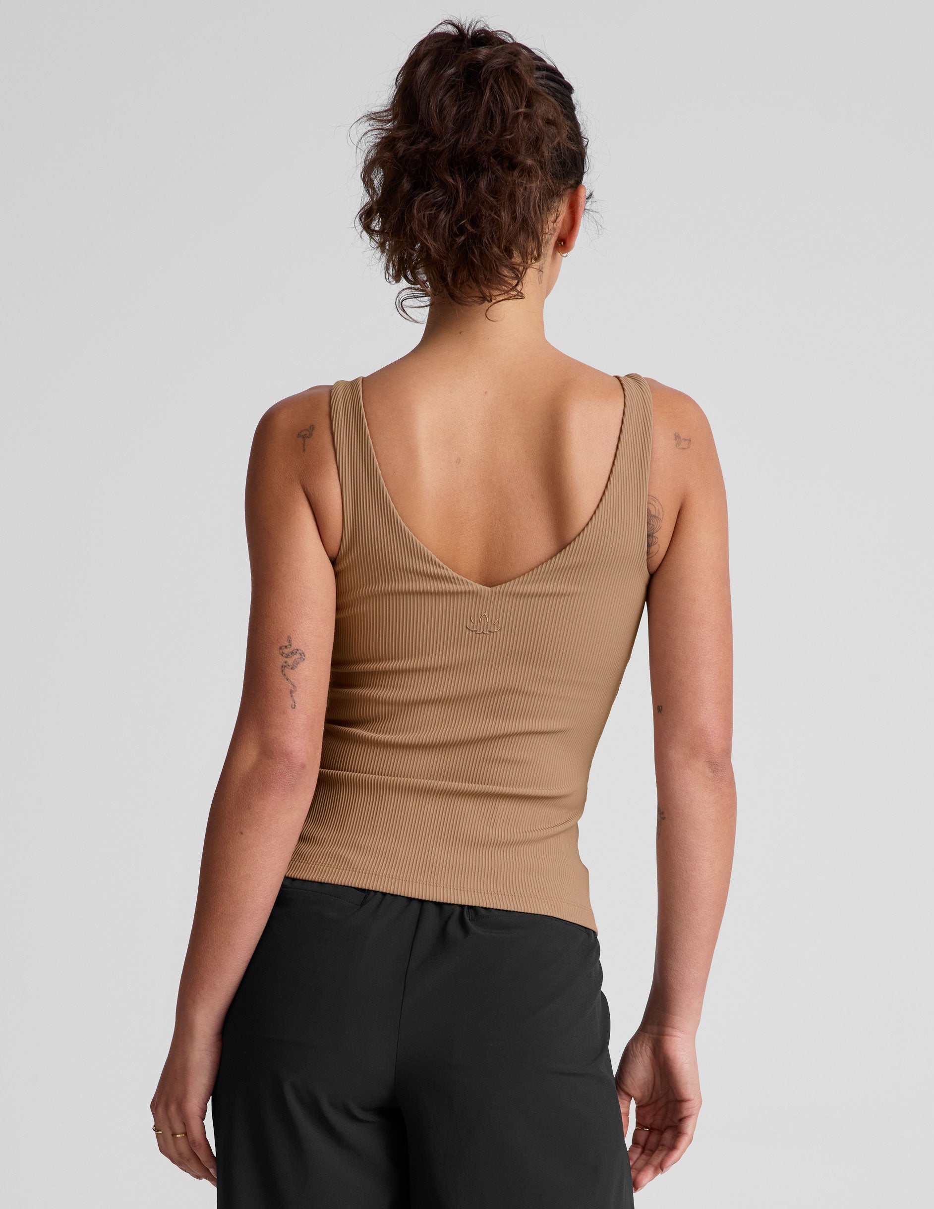 brown classic length tank top with a soft V neckline front and back​, overlapping front neckline detail, and a performance lining shelf bra. Tank hits at a high hip length. 