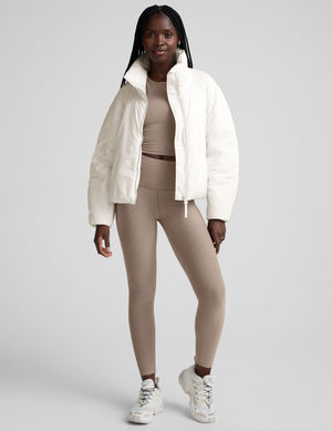 model wearing a white puffer jacket against a plain background. 